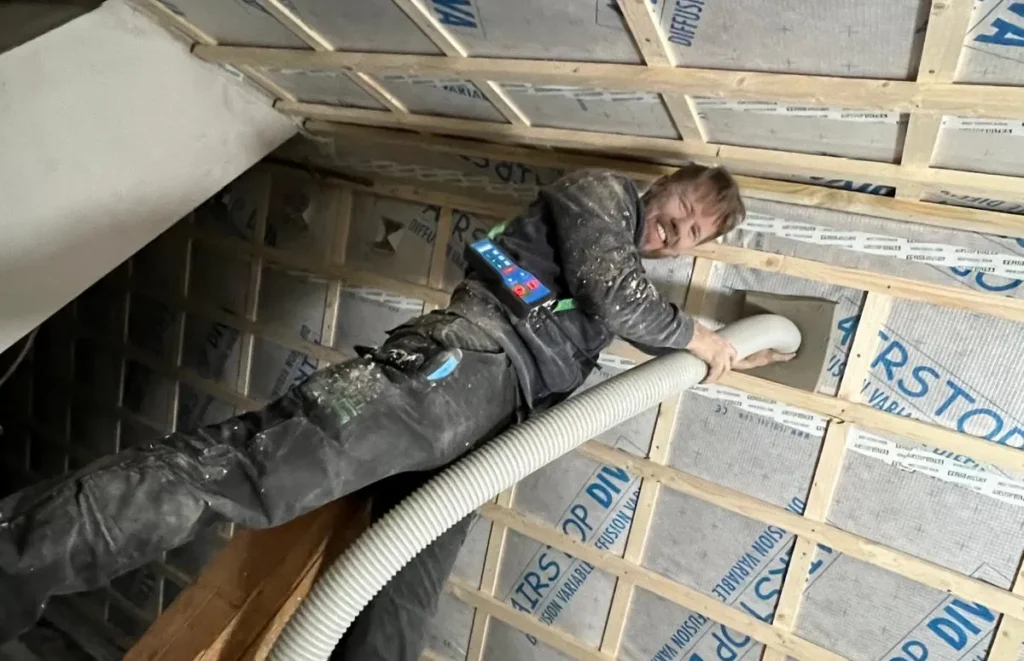 Mitarbeiter von Meyer Dach & Wand Design bläst Cellulose-Dämmung in ein Dach ein
