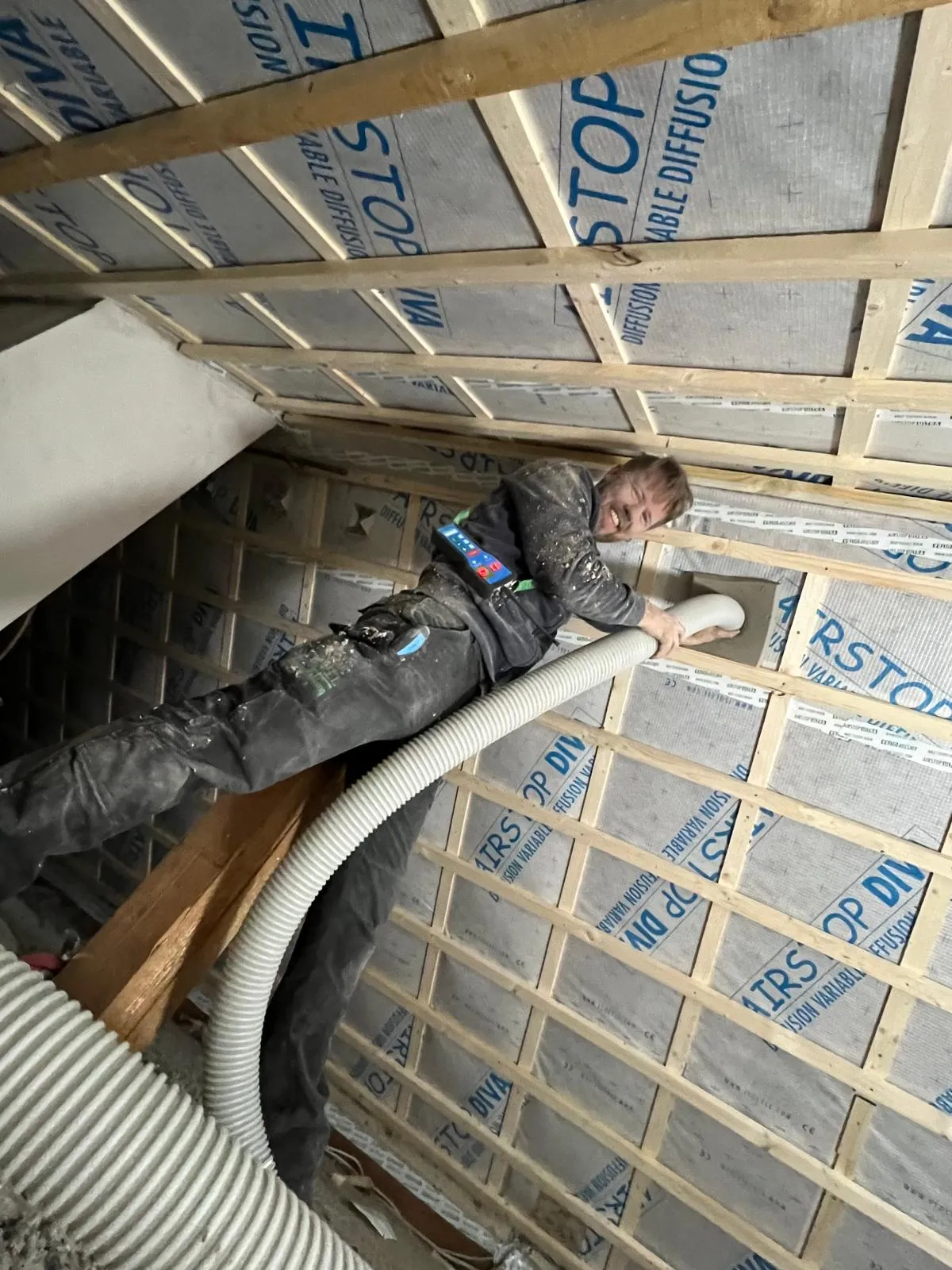 Dachdecker bläst Cellulose-Dämmung in die Dachschräge ein